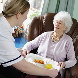 Nurse serving a meal on a tray to a resident.
